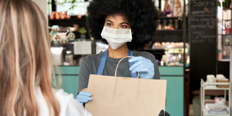 Business owner handing out a paper bag to a customer. 