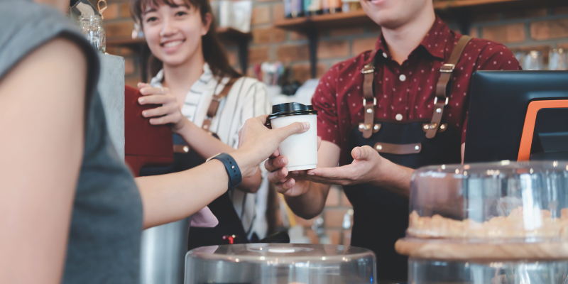 Barista serving a cup of coffee to customer.