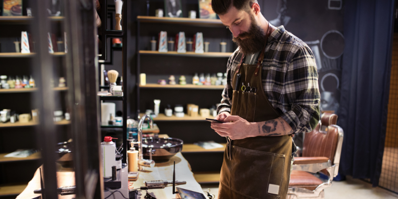 Barber sending an appointment reminder through phone.