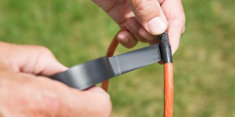 Person wrapping electrical tape on a wire.