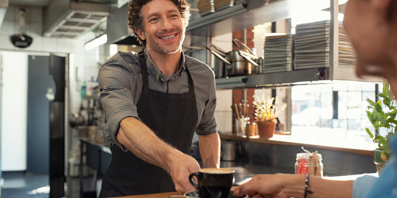 coffee shop owner serving a customer.