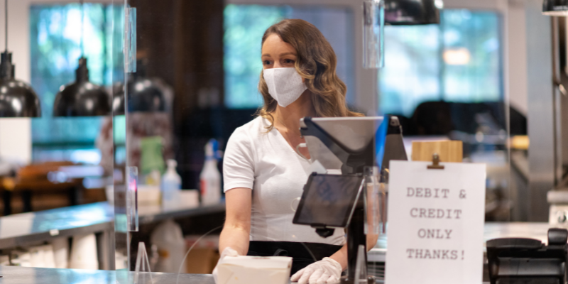 Employee at the counter wearing a mask and gloves.