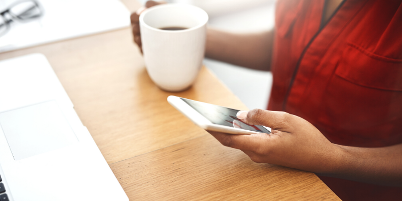 Business owner having coffee while texting a customer.