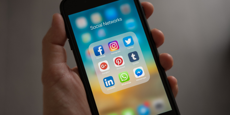 Person holding a phone showing various social me