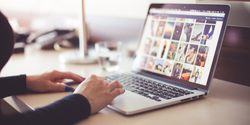 Woman uploading photos to social media on her laptop.