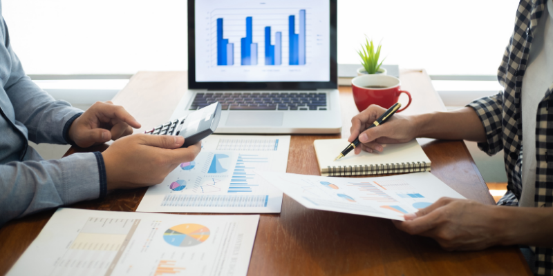 what is meant by business plan appraisal Two people sharing a table with financial statements laid out, a calculator, and a computer.