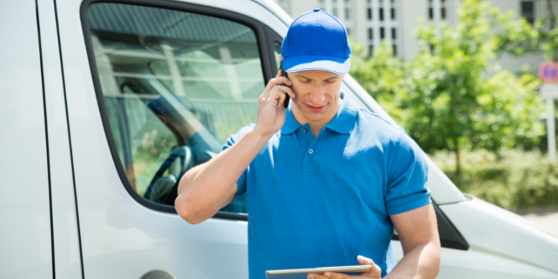 Plumber on the phone outside of a job site next to his company van.
