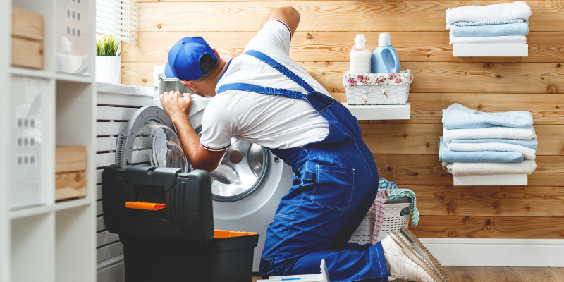 Plumber working on a laundry machine.