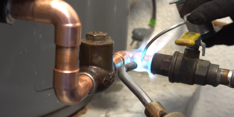 Plumber soldering a pipe with a torch.