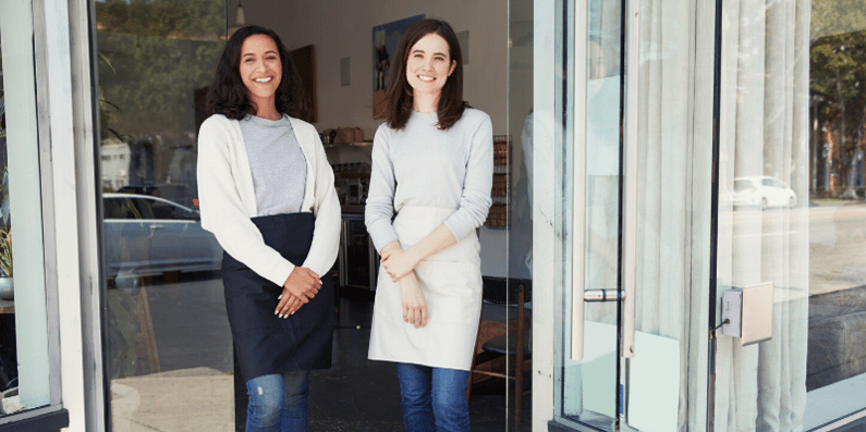 Two business owners standing in front of their business.