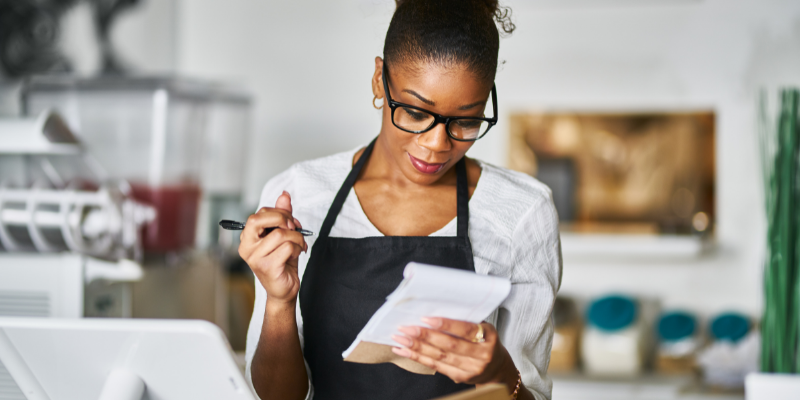 small business owner looking at a notepad by the front counter.