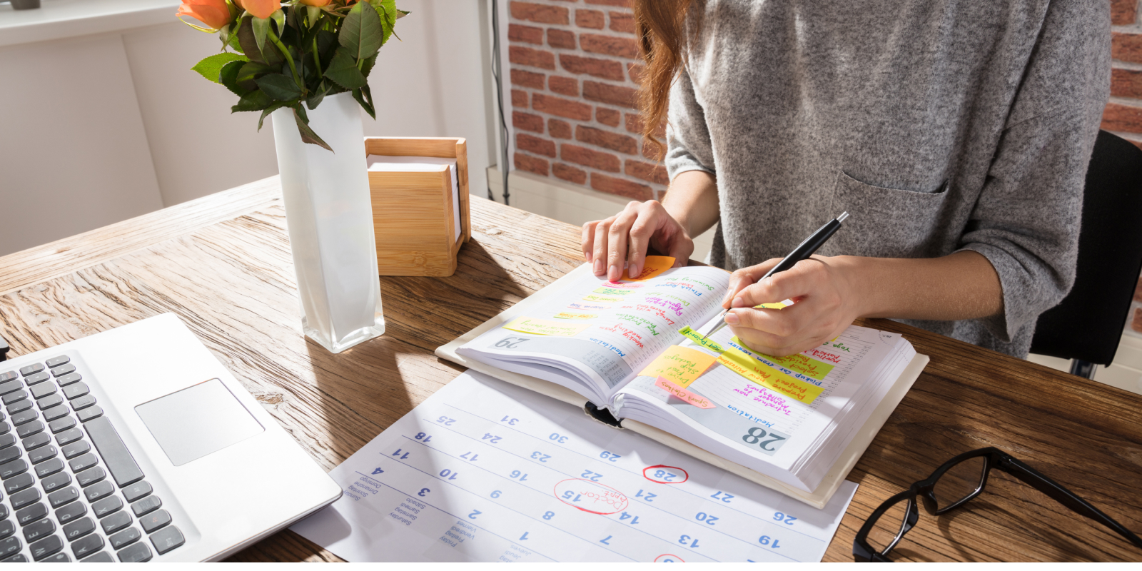 woman at her desk writing notes in a planner
