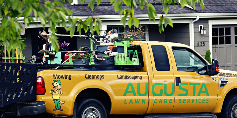 A branded Augusta Lawn Care truck parked in front of a house.