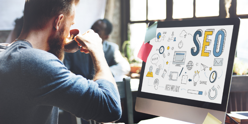 man drinking coffee looking at a computer screen that says seo