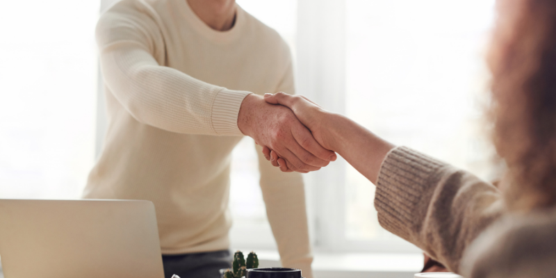 A man and a woman shaking hands, forming a business partnership. 