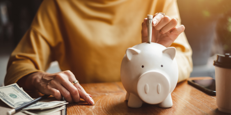 Business owner putting a bill in a piggy bank.