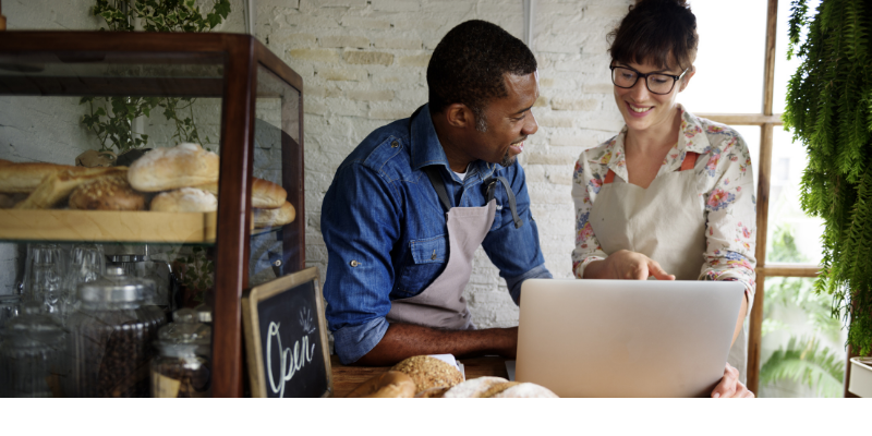 man and woman talk in front of a computer screen