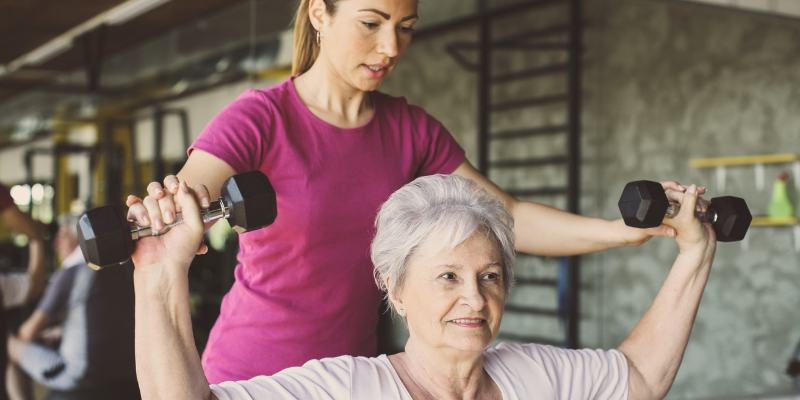 Personal trainer working with an elderly woman.