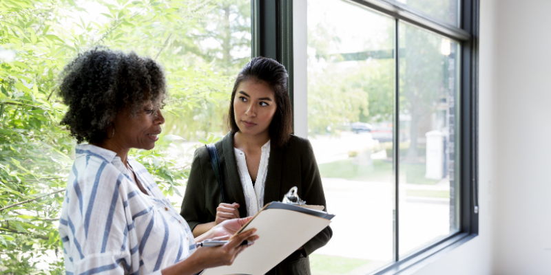 Business owner having a conversation with her employee by a window.