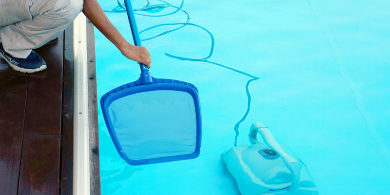 Worker cleaning a pool with a net.
