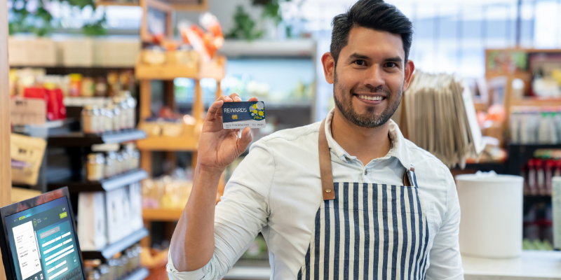 Store clerk holding up a loyalty rewards card.