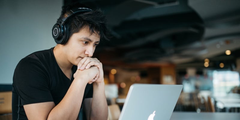 Photo of a man thinking in front of a laptop. 